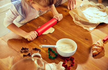 Top view image with baking items on kitchen table. Little girl, child cooking with her mother,...