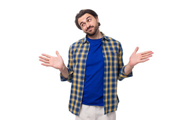 Naklejka premium a young caucasian brunette man with a beard and an earring is dressed in a blue plaid shirt and t-shirt actively gesticulates and points with his hands