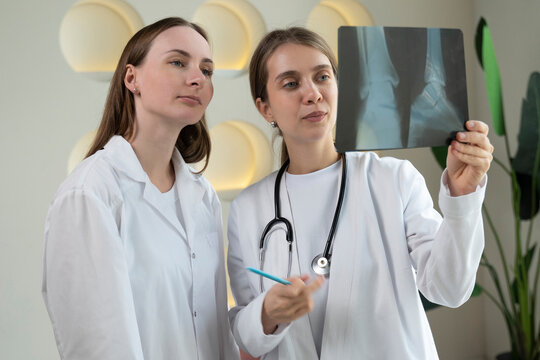 Two female doctors look at the patient's X-ray in the clinic