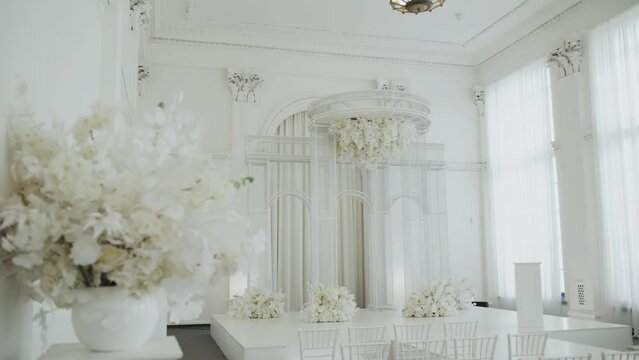 Medium shot wedding arch decorated in white color and white floral composition. Wedding concept, slow motion