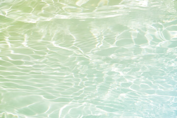 Bluewater waves on the surface ripples blurred. Defocus blurred transparent blue colored clear calm water surface texture with splash and bubbles. Water waves with shining pattern texture background.