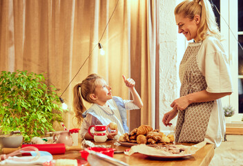 Delicious cookies and pastry. Happy young woman, mother cooking sweet, baking with her little daughter at home in winter. Concept of cookie day, motherhood, childhood, holidays, family