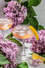 Rose wine in glass with blooming lilac on a light background