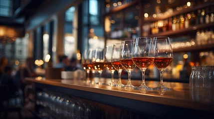 Fotobehang Filled wine glasses on a wooden bar with a blurred restaurant background © Alex Bur