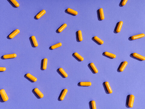 Top view pattern orange pills on violet background