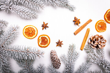 Dried orange, anise and pine cones on a white snow-covered background among snow-covered Christmas...