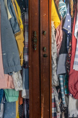 Fototapeta na wymiar Clothes hang on hangers in an old wardrobe