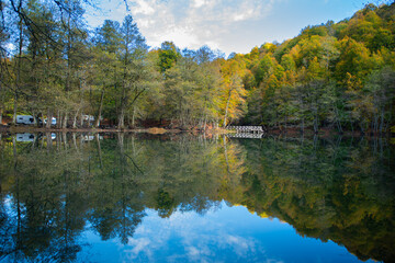 Fototapeta na wymiar Yedigöller or Seven Lakes National Park is in Turkey. Reflection of a lake with trees and blue sky in autumn colors. Yedigöller, Bolu. Yedigöller in autumn. Bolu, Türkiye.