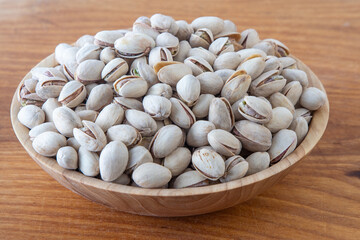 Pistachios in a wooden bowl. Wooden background. Healthy food
