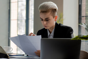 Confident businesswoman holding paper documents in office. Woman analyzing facts reading materials....
