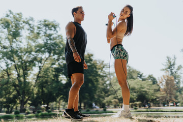 Obraz premium A Caucasian couple jumping rope in a park, showcasing their fit bodies and dedication to a healthy lifestyle. They warm up, stretch, and engage in a challenging training session.