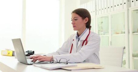 General practitioner in hospital uses laptop computer to print prescription