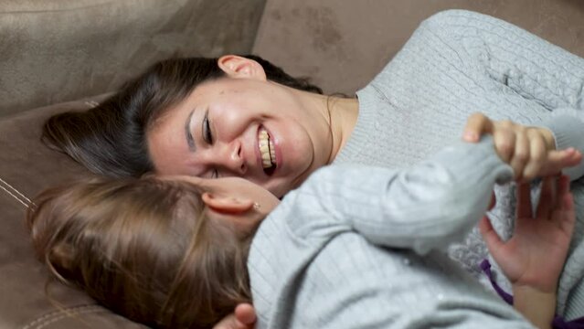 Happy mother and cute little daughter tickling laughing having fun