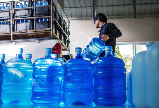 Workers lift drinking water .clear and clean in blue plastic gallon into the back of a transport truck purified drinking water inside the production line to prepare for sale. small business