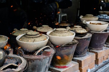 Traditional clay pots on fiery charcoal stoves at Heun Kee Claypot Chicken Rice — Jalan Yew,...