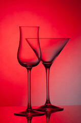 Empty glass wine glass on a red background..Wine glass for a drink on a red background. Dark silhouette of a glass.