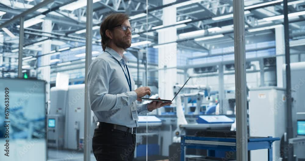 Poster Portrait of a Young Factory Manager Working on Laptop at an Industrial Manufacture with Autonomous Assembly Robots. Specialist Monitoring Production on a Computer, Planning Workload for the Shift