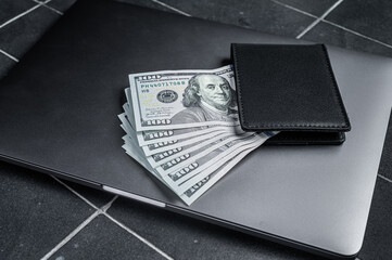 Corporate business desktop with laptop, digital tablet, wallet, money and cup of coffee. Black...