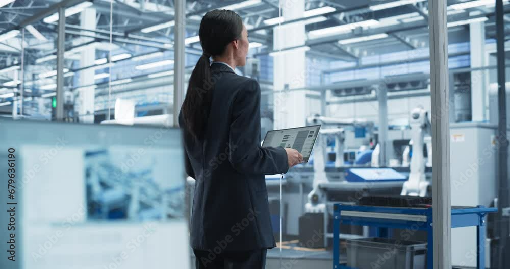 Aufkleber experienced female engineer standing in office, using laptop computer and overlooking production at 