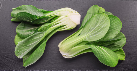 Fresh bok choy or chinese cabbage on slate stone cutting board. Top view. - obrazy, fototapety, plakaty