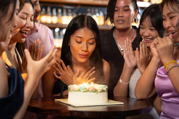 Beautiful Asian Woman is Savoring Her Birthday Festivities at a Restaurant or Bar, Surrounded by...