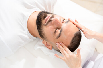 Fototapeta na wymiar Male face massage for reducing puffiness by professional massage therapist in beauty clinic