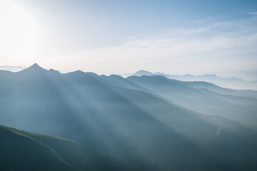 Panoramic view of sun rays over mountain at sunrise, high in the alps