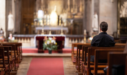 A man sitting in a church looking at the alter