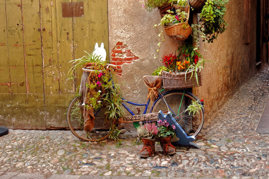 A bicycle decorated with flowers outside a shop.