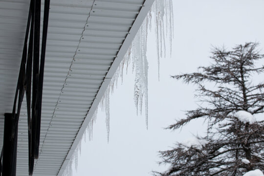 Icicles hanging from the roof of the house. Picture of winter snowy Magadan city, Russia.