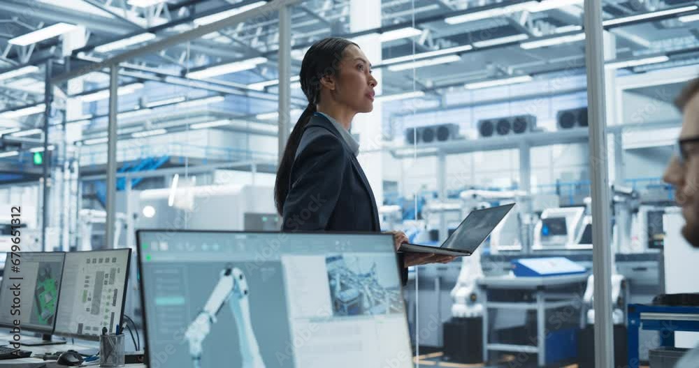 Leinwandbilder System Administrator Working on a Desktop Computer at a Modern Manufacturing Plant. Focus Switching to a Female Software Developer Programming the Work of the Robotic Arms on Assembly Conveyor