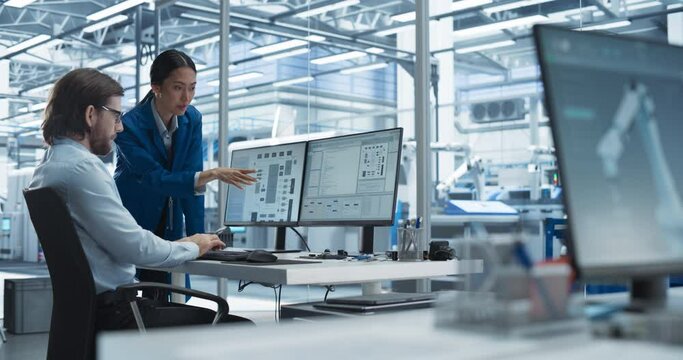 Experienced Male Engineer and Asian Chief Technology Officer Working at a Modern Industrial Factory, Using Computer and Discussing Production of Modern Electronics for Artificial Intelligence Machines