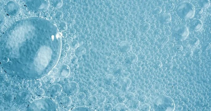 Oxygen bubbles in water on a blue abstract background on super slow motion.