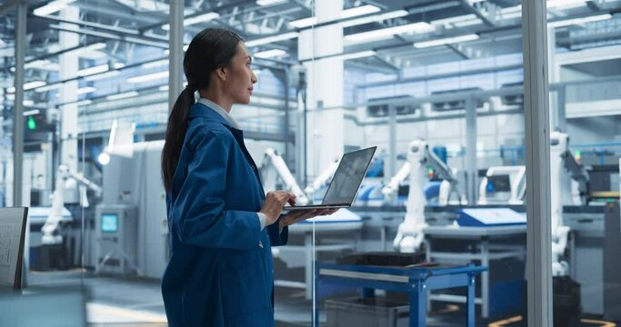 Southeast Asian Engineer Using Laptop Computer and Looking Around a Factory Facility with Equipment Producing Modern Electronic Components for Advanced Industrial Needs