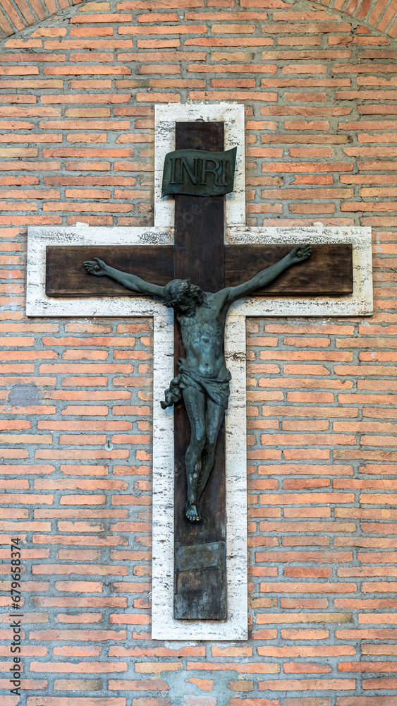 Wall mural Big metal crucifix decorating external brick wall of italian church