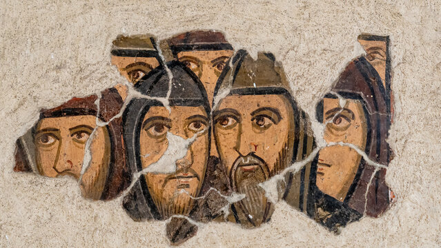 Close-up on parts of medieval fresco representing a group of male faces
