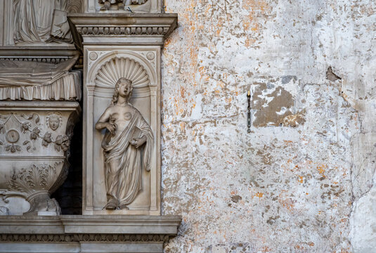 Detail of sculpture carved in marble representing a bare-breast woman decorating the exterior facade of old building in Rome