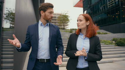 Caucasian middle-aged businesswoman and adult woman business coworkers partners businessman formal communication talking discuss project startup walking in city corporate talk outdoors colleagues
