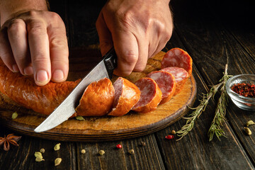 A man hands use a knife to cut meat sausage for making sandwiches. Delicious fast food idea for a snack.