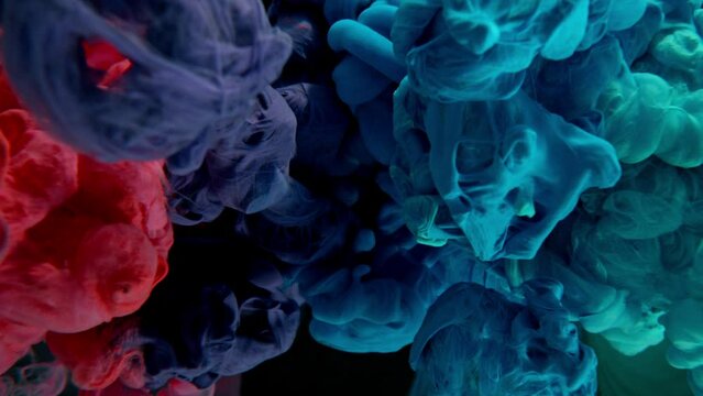 Super Slow Motion of Colored Paints Mixing in Water. Isolated on Black Background. Filmed on High Speed Cinema Camera, 1000fps. Speed Ramp Effect.