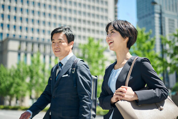 ビジネス街を歩く50代男性会社員と30代女性会社員