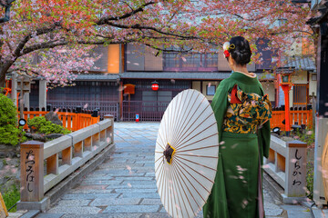 Young Jpanese woman in traditional Kimono dress strolls on Tatsumi bashi bridge (Japanese text on...