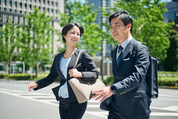 ビジネス街を歩く50代男性会社員と30代女性会社員