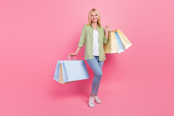 Full size photo of cheerful pretty aged lady hands hold store mall shopping bags isolated on pink color background