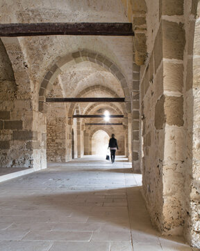 Ancient stone hallway in the Citadel of Qaitbay, Alexandria, Egypt. The hallway is lit by natural light streaming in through narrow windows, and the walls are made of stone bricks