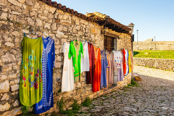 Hanging beautiful traditional dresses different colors and decoration at market, bazaar, fashion in old city of Albania - obrazy, fototapety, plakaty