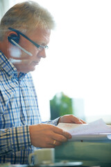 Man, paperwork and headset for communication in office for career in telesales, customer care or tech support. Mature agent, call centre and document for reading, review or report for consumer growth