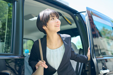 タクシーから降りる30代女性会社員