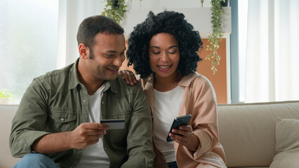 Multiracial African American Arabian family hold mobile phone and bank credit card online shopping...
