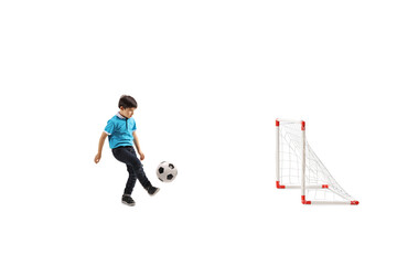 Fototapeta premium Full length shot of a little boy playing soccer with a mini goal